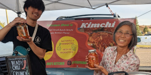 Mama Boo's Kitchen vendors showing off jars of kimchi.