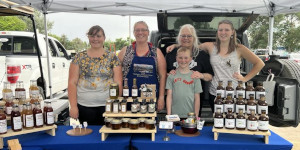 5 people standing behind table of canned goods