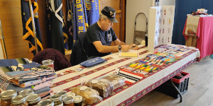 Man working at a table with baked goods and crafts.