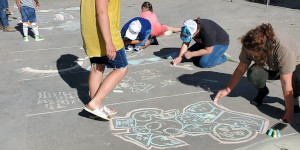 People drawing with chalk on sidewalk