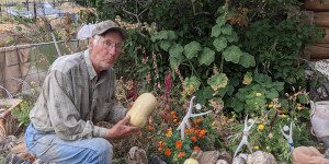 Man kneeling and holding a squash.