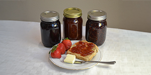 Jars of jam with plate of toast and fresh fruit
