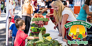 Woman helping child at a farmers' market.