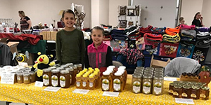 Two children standing behind table with canned goods.