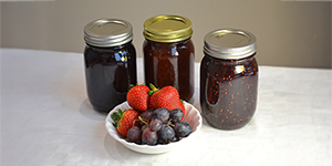 Jars of jam and a bowl of fresh fruit