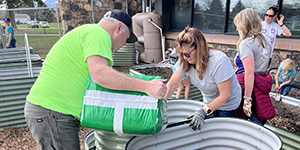 People filling metal tanks with garden soil