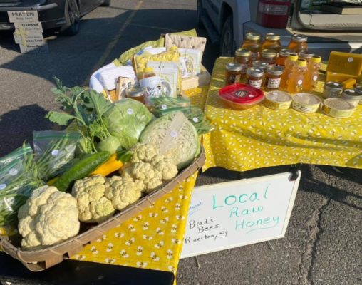Jars of honey, honey products and produce arrange on tables.
