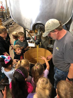 Adult and children watching honey processing.