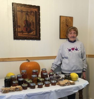 Woman standing beside table with produce and canned goods