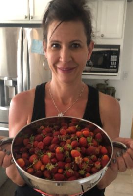 Woman holding a bowl of raspberries.