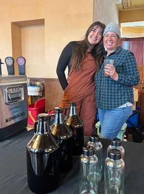 Two women in a shop with a kombucha machine