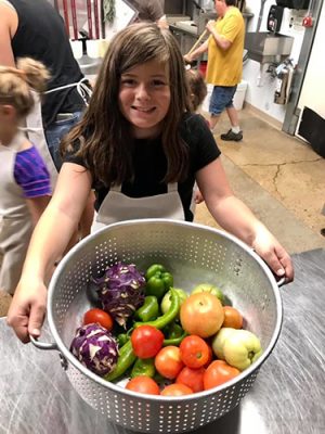 Girl holding pan of vegetables