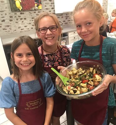 Three girls holding a salad