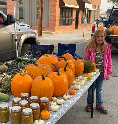 Child with pumpkins and canned produce.