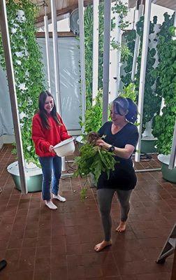 Two women standing next to vertical garden