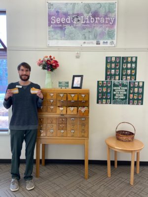 Man displaying seeds in a library.