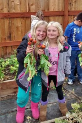Two girls holding vegetables.