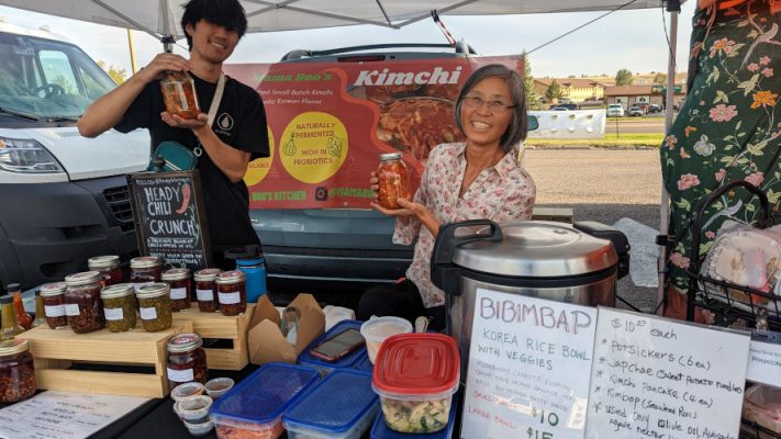 Mama Boo's kitchen vendors showing off jars of kimchi.