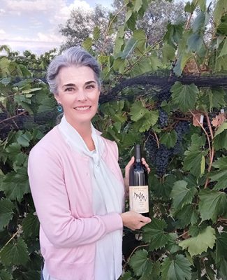 Woman holding wine bottle in a vineyard