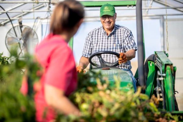 Woman watching man drive a tractor