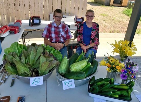 Two people sitting at a table with fresh produce