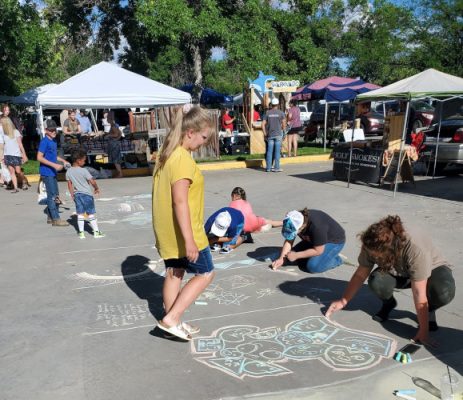 Farmer's market with people making chalk drawings.