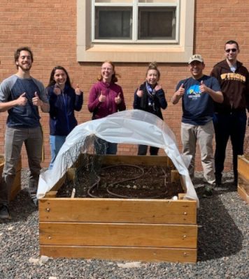 Students standing behind a raised garden box