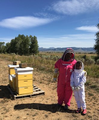 Adult and child standing next to honey boxes