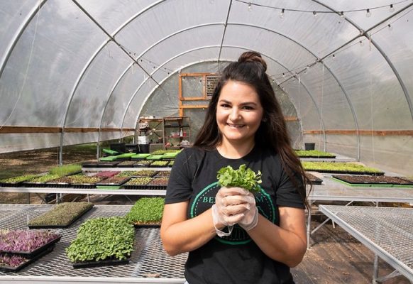 Woman holding plant in a greenhouse