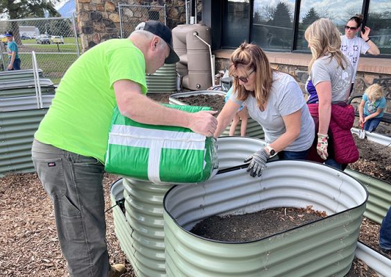 People filling a metal tank with garden soil