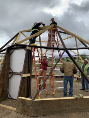 People constructing high tunnel structure