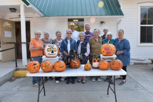 Women standing behind table with pumpkins