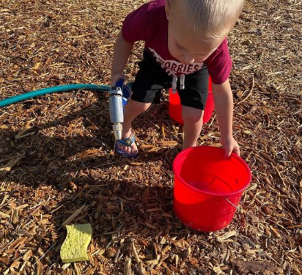 Worland-Community-Garden-1-500h Child with hose and a bucket.